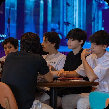 Grupo de jovens reunidos em uma mesa com livros em cima.